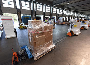 In der Umschlaghalle von Streck Transport in Freiburg werden Paletten auf Hubwagen zur Verladung zu wartenden Lkws transportiert 