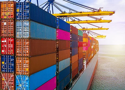 Ein großes Schiff mit vielen Containern wird im Hafen mittels Kränen entladen