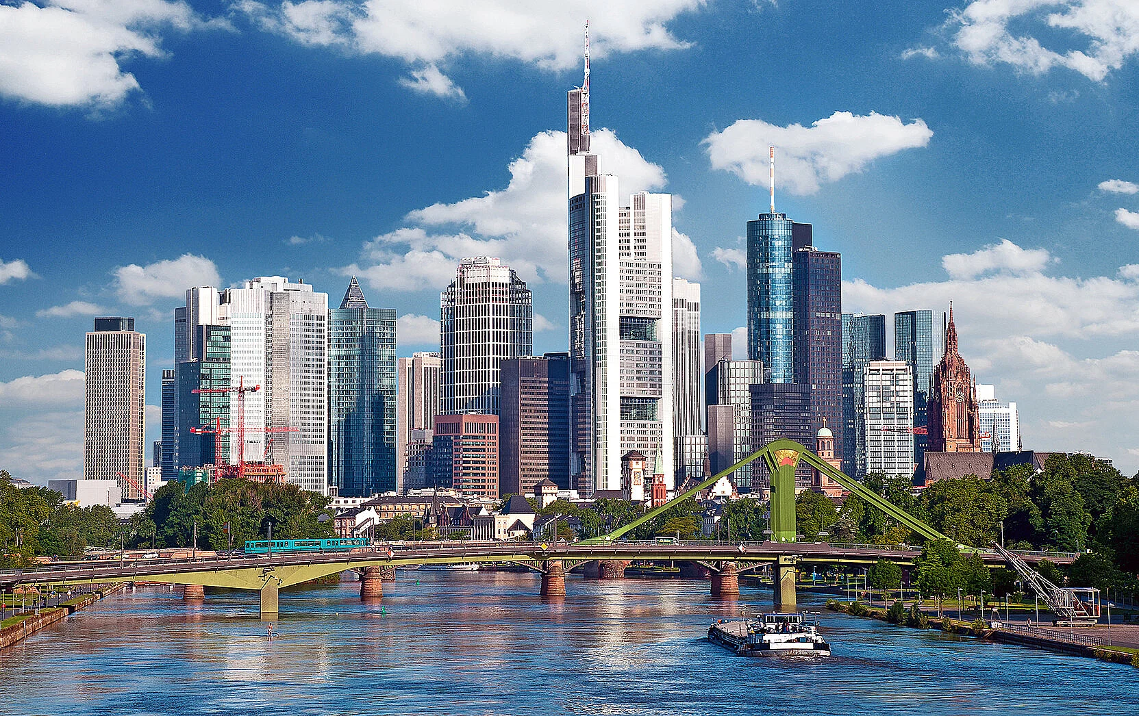 Skyline der Wolkenkratzer von Frankfurt am Main, im Vordergrund der Main mit einem Frachtschiff und einer Brücke