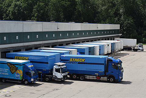 Mehrere Lastwagen parken an der Laderampe einer Halle bei Streck Transport in Freiburg