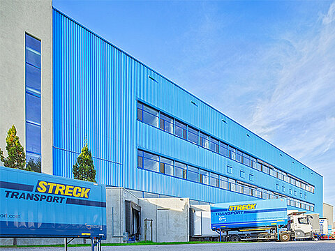 Außenansicht der blauen Halle für Luft- und Seefracht von Streck Transport in Freiburg mit Wechselbrücken und Lkws