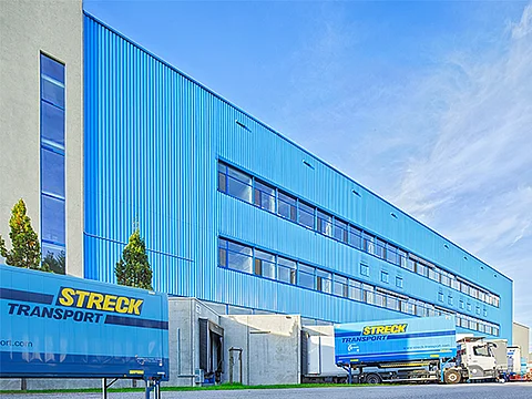 Außenansicht der blauen Halle für Luft- und Seefracht von Streck Transport in Freiburg mit Wechselbrücken und Lkws
