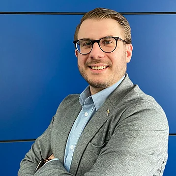 Lars Intraschak, Verkaufs-Außendienst, steht vor einer blauen Wand