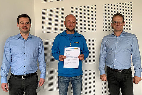 Lagermeister Kai Grötzbach präsentiert die Urkunde zur Ernennung als Ausbilder für den Hochregalstapler zusammen mit Logistikleiter Fabian Weber und Streck Transport-Geschäftsführer Gerald Penner