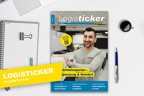 Die 64. Ausgabe der Streck Transport-Kundenzeitschrift LogisTicker liegt auf einem Schreibtisch mit Kugelschreiber, Notizblock und Kaffeetasse