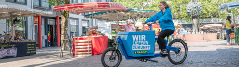 Streck Transport-Lastenrad Lörrach Eine Mitarbeiterin von Streck Transport fährt auf dem Lastenrad in der Lörracher Innenstadt