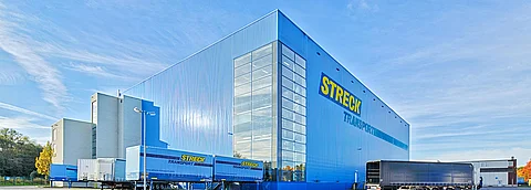 Die blaue Halle von Streck Transport in Freiburg mit Wechselbrücken im Sonnenschein