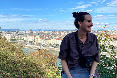 Viola Wehrle, DHBW-Studentin bei Streck Transport, sitzt auf einer Anhöhe mit Blick auf die ungarische Hauptstadt Budapest