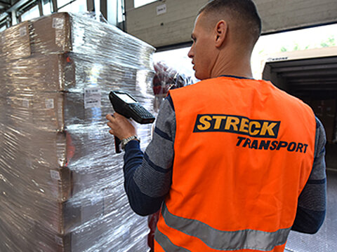 Ein Mitarbeiter von Streck Transport scannt eine Palette vor dem Laden auf einen Lkw