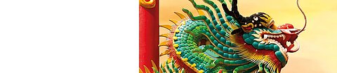 Ein bunter chinesischer Drachen vor einem orange-gelben Himmel
