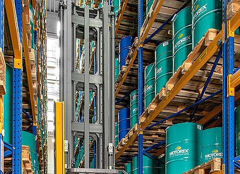 Im Hochregallager von Streck Transport in Freiburg lagern blaue Fässer und Paletten