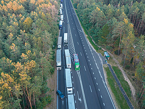 Lkws warten auf einer sechsspurigen Straße in einem Wald vor einem Grenzübergang