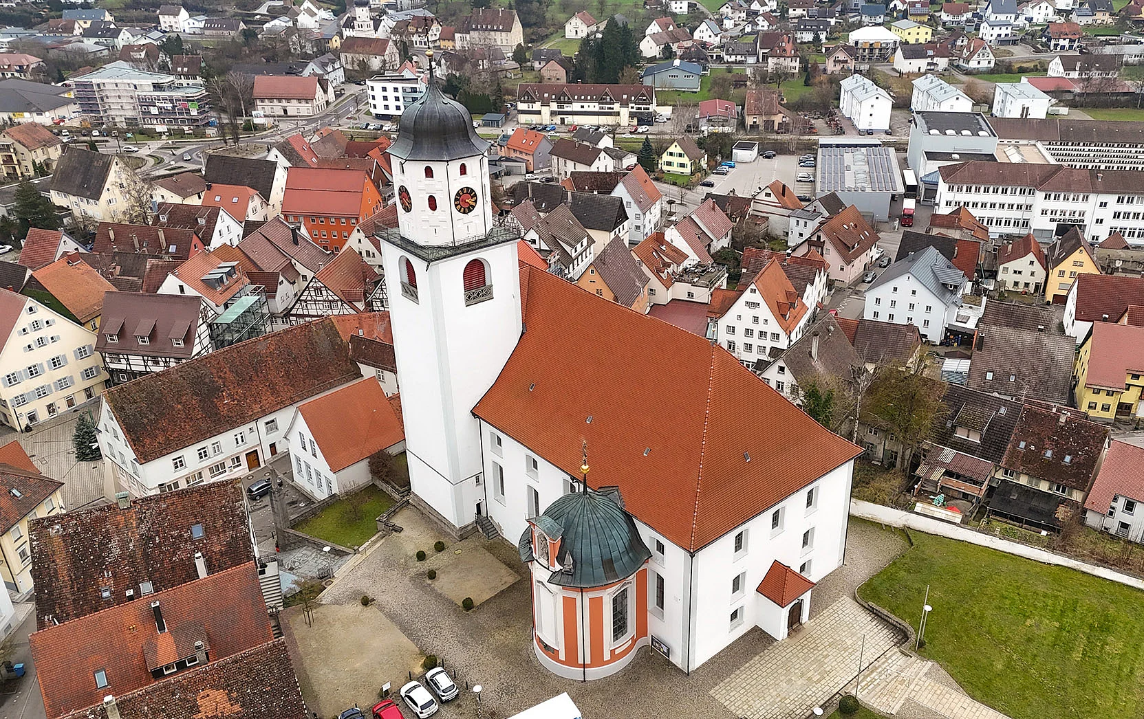 Ansicht der Stadt Meßkirch bei leicht bewölktem Himmel, im Vordergrund eine grüne Wiese, im Hintergrund Gebäude, das Schloss und eine Kirche