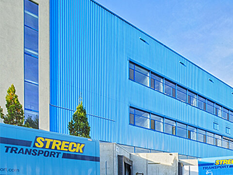 Außenansicht der blauen Halle für Luft- und Seefracht von Streck Transport in Freiburg mit Wechselbrücken und Lkws