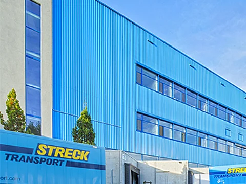 Außenansicht der blauen Halle für Luft- und Seefracht von Streck Transport in Freiburg mit Wechselbrücken und Lkws