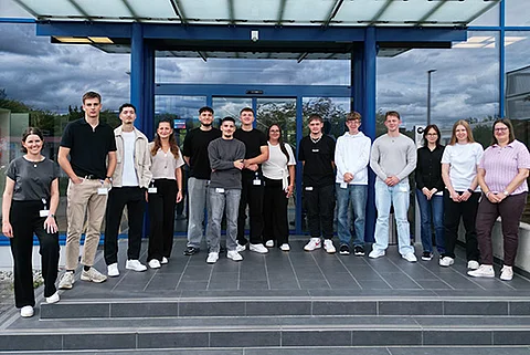 Zwölf Auszubildende des Jahrgangs 2025 von Streck Transport mit ihren beiden Ausbilderinnen in Freiburg vor dem Kundenzentrum