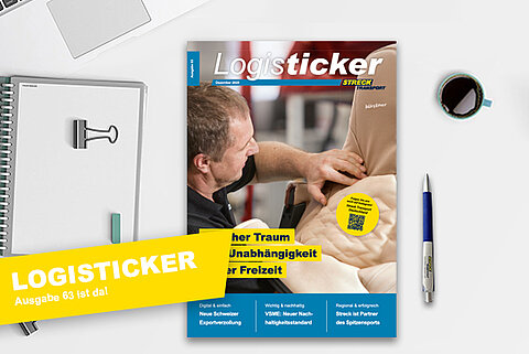 Die 63. Ausgabe der Streck Transport-Kundenzeitschrift LogisTicker liegt auf einem Schreibtisch mit Kugelschreiber, Notizblock und Kaffeetasse