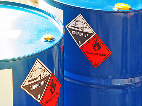 zwei blaue Fässer mit Gefahrstoff-Aufkleber, Corrosive, Flammable Liquid