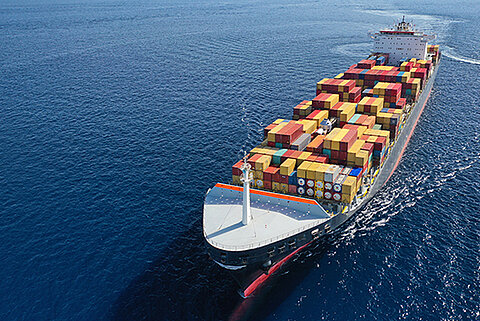 Ein großes Schiff mit vielen Containern auf hoher See bei gutem Wetter