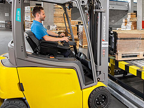 Ein Mitarbeiter von Streck Transport sitzt auf dem Gabelstapler und lädt eine Holzkiste auf ein Förderband